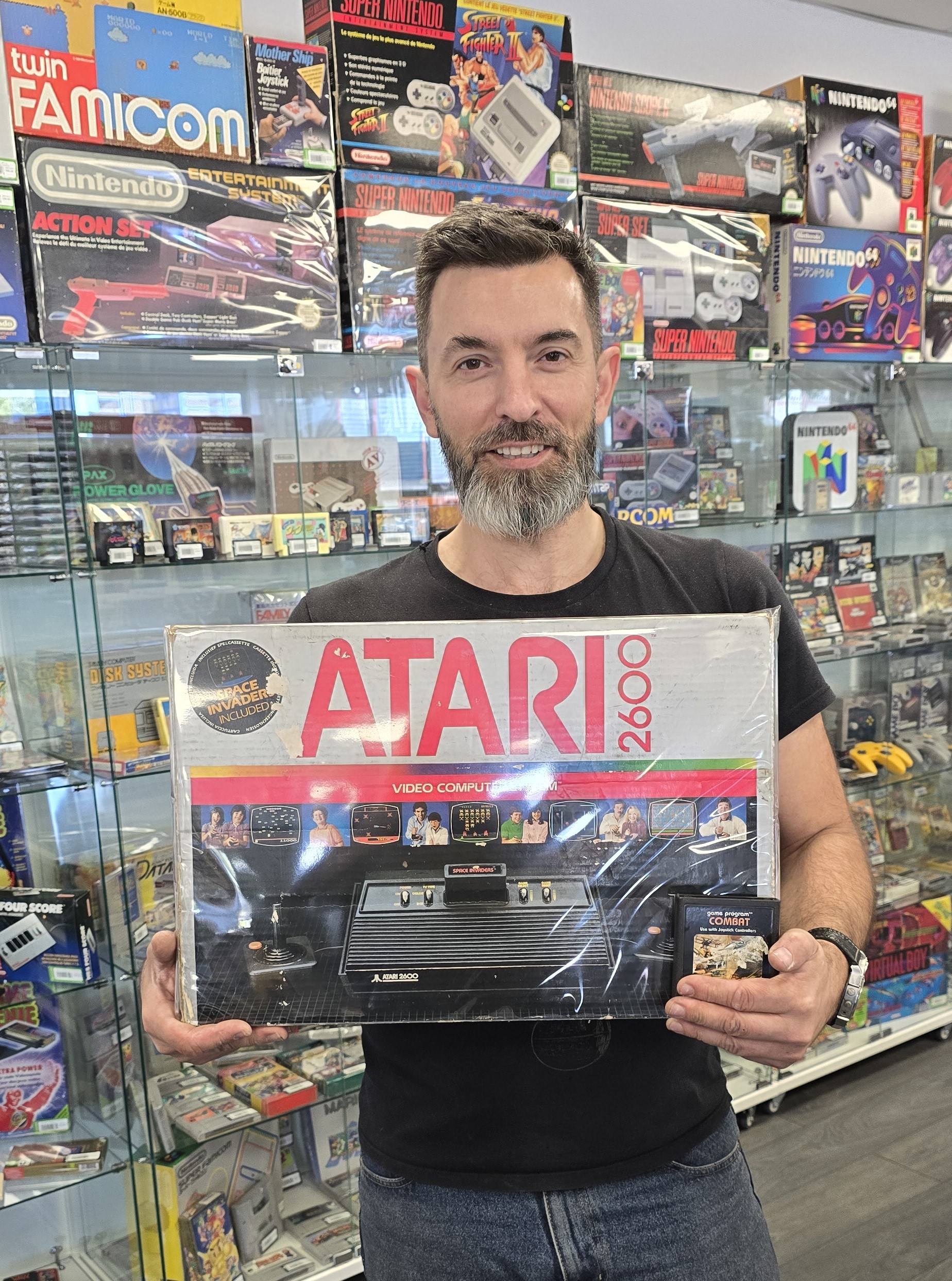 Sebastien Esch, nouveau franchisé Gamecash Strasbourg, pose dans son rayon rétrogaming avec sa première console, une Atari 2600